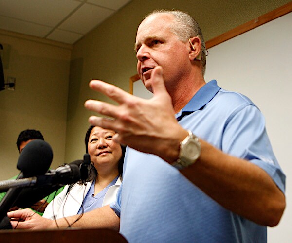 rush limbaugh speaks at a news conference, gesturing with both arms extended