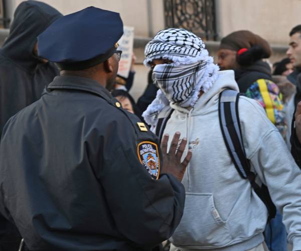 an nypd officer talks to a protester with other protesters around them