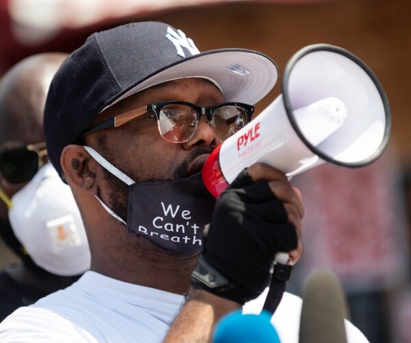 terrence floyd in a we can't breathe mask pulled down to his neck speaking into a white megaphone