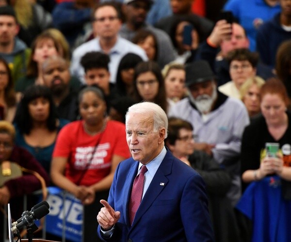 biden speaks at a campaign rally with a diverse crowd behind him