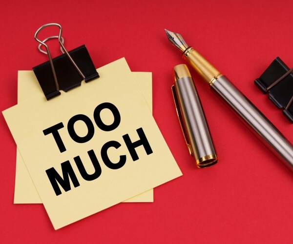 on a red background, a pen and stickers with the inscription too much
