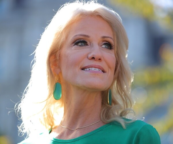 conway in a green top and green earrings standing outside