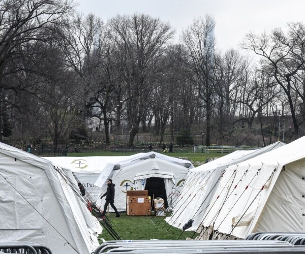 white tents in central park nyc with the samaritan's purse logo on them with trees in the background