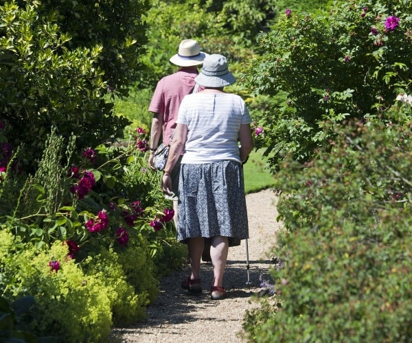 elderly couple walking with canes on a path