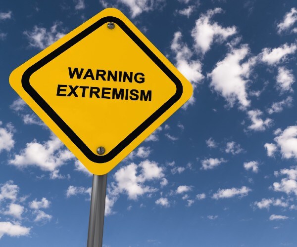a road sign reading extremism ahead against a cloudy blue sky