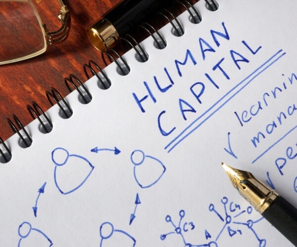 notepad with human capital on a wooden surface