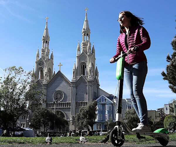 a woman rides a motorized scooter in Washington Square Park in San Francisco
