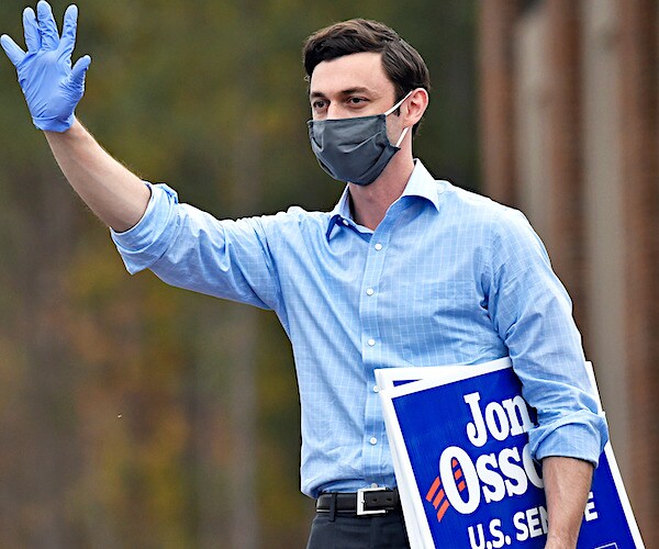 jon ossoff waves a covid-19 gloved hand and holds a campaign placard during a campaign ground game appearance