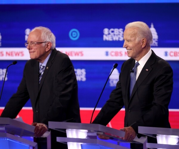 biden and bernie sanders at the cbs dem deabte standing and smiling at the podiums
