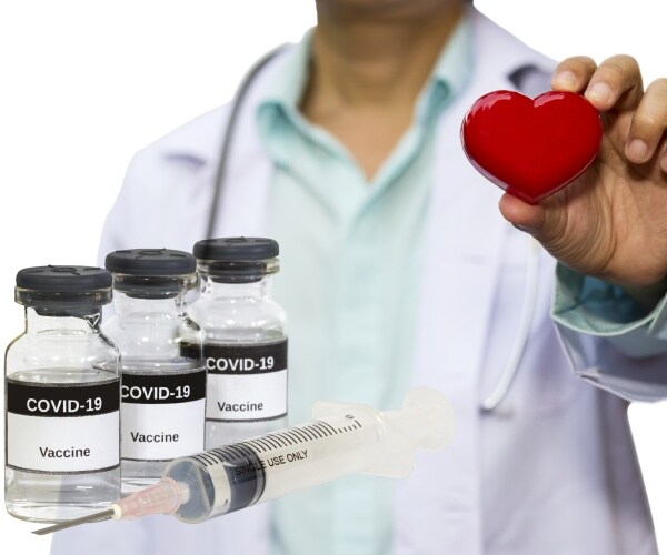 vials of COVID-19 vaccine, syringe and healthcare worker holding up a heart