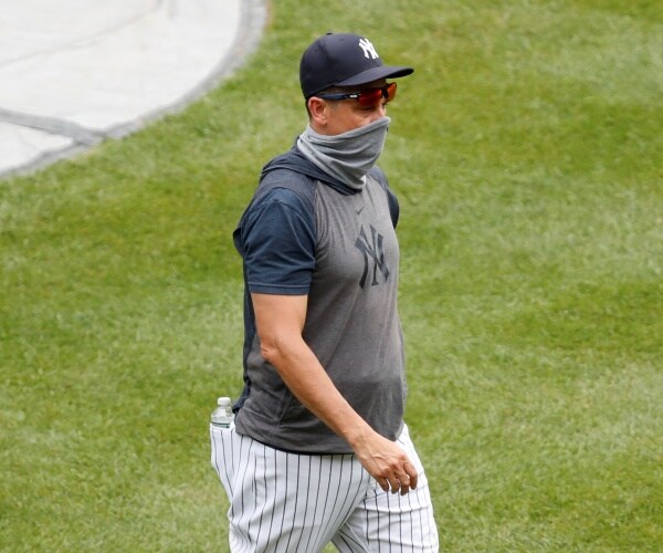 man wears a gray neck gaiter as he walks on lawn