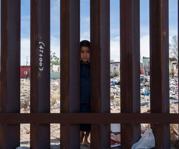 someone looks through the border wall between mexico and u.s.