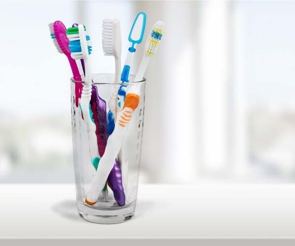 colorful toothbrushes are shown in a clear glass cup 