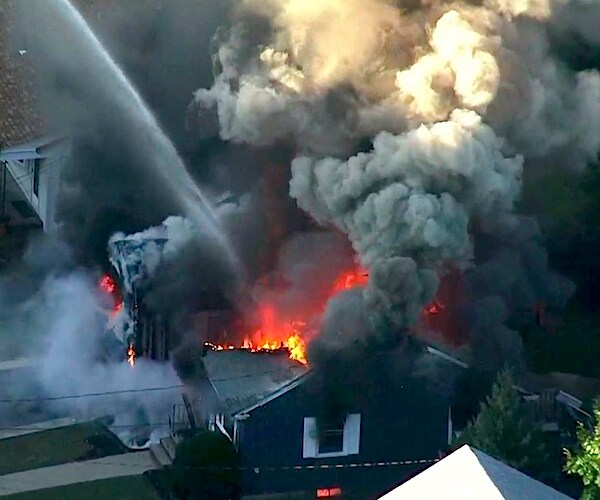 Flames consume the roof of a home following an explosion in Lawrence, Massachusetts