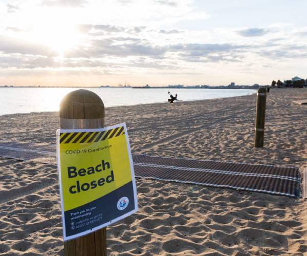 sign on empty beach reads beach closed