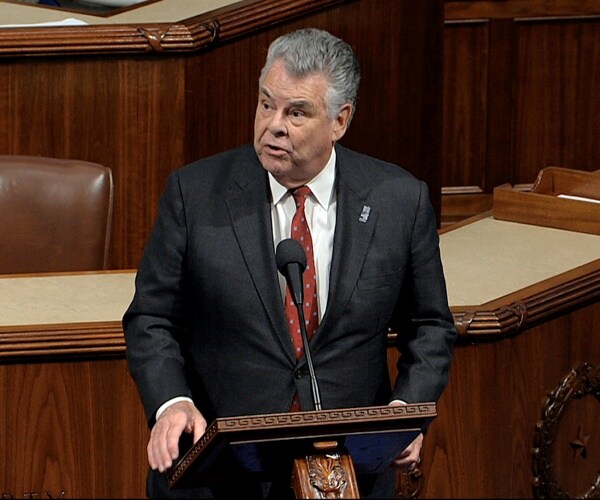 peter king at a podium speaking wearing a suit and red polka dot tie