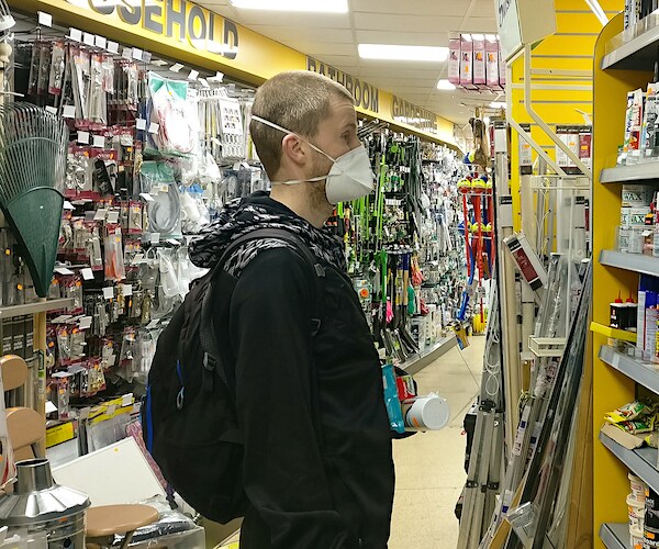 Young man with respirator face mask and gloves shopping household items