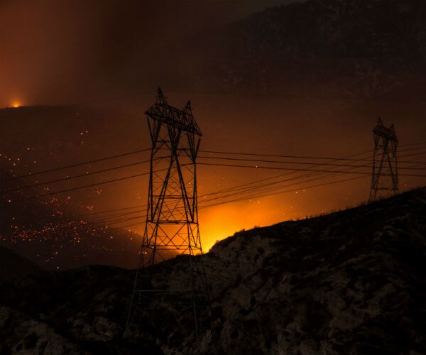 fire at night beneath high transmission power lines