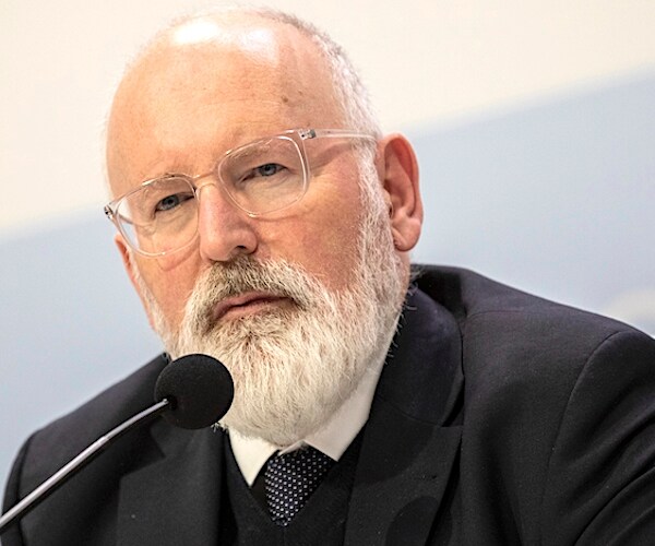 Frans Timmermans sits and looks to the left as he speaks behind a mic during a news conference
