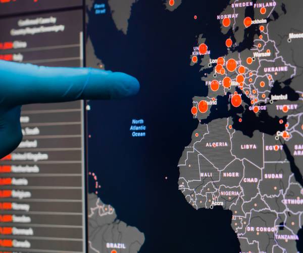 gloved hand pointed at map of Europe with virus outbreaks indicated