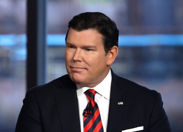 bret baier stands on a stage at a town hall event