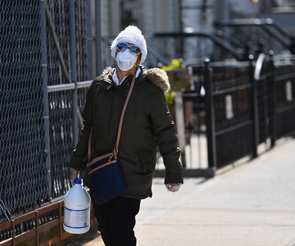 a woman walks down a street carrying bleach