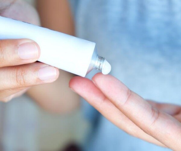 two hands putting on antifungal cream in a tube
