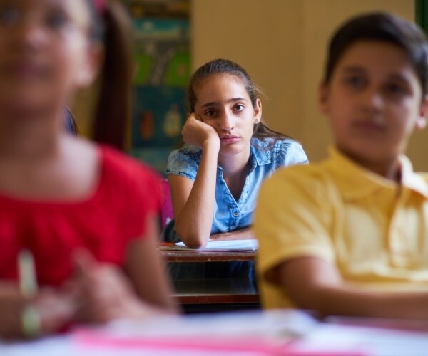 child looking sad/anxious in a classroom in school