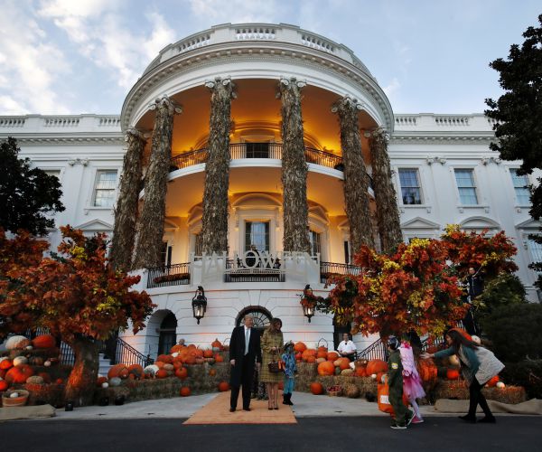president donald trump and first lady melania trump give candy to children during a halloween trick-or-treat event.