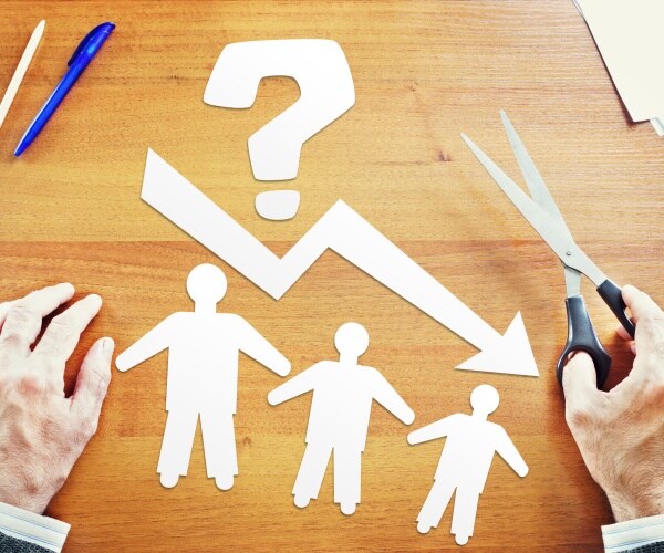 paper cutouts of people with arrow pointing down symbolizing a reduction in population