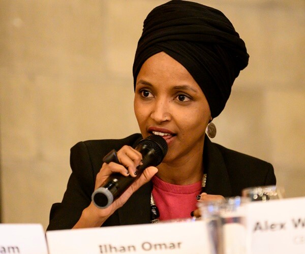 rep. ilhan omar speaks at a panel, holding a mic