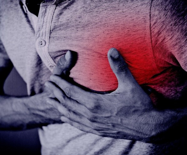 close-up of chest of young man holding hand over heart in pain