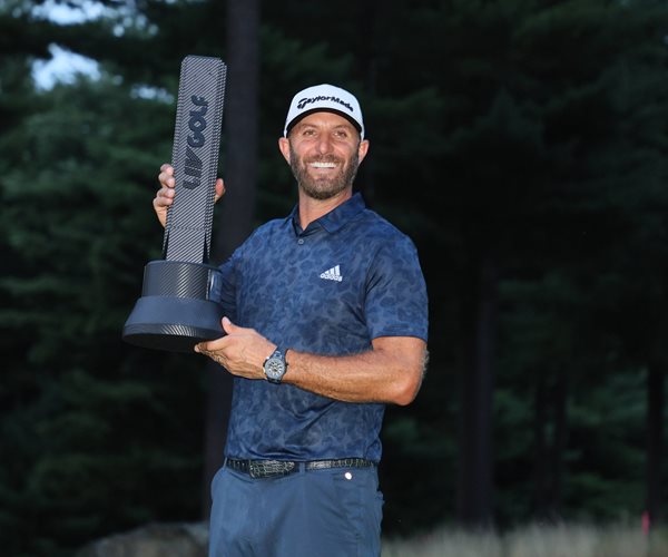 dustin johnson poses with trophy