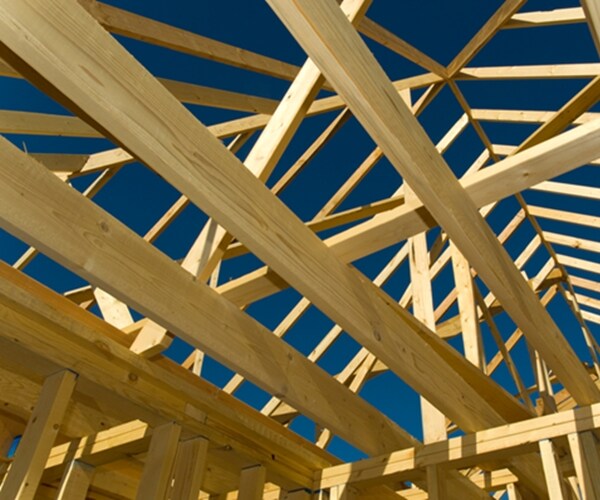 new home under construction with wood, trusses and supplies against blue sky 