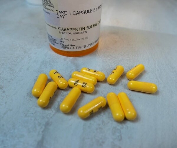 prescription vial of gabapentin, plus capsules on table
