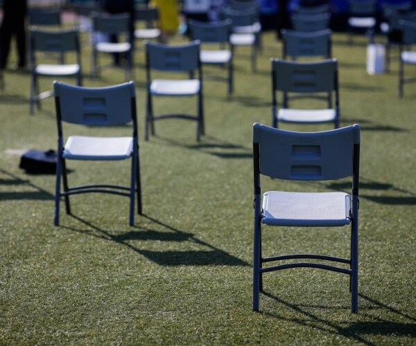 folding chairs out on a field spaced apart
