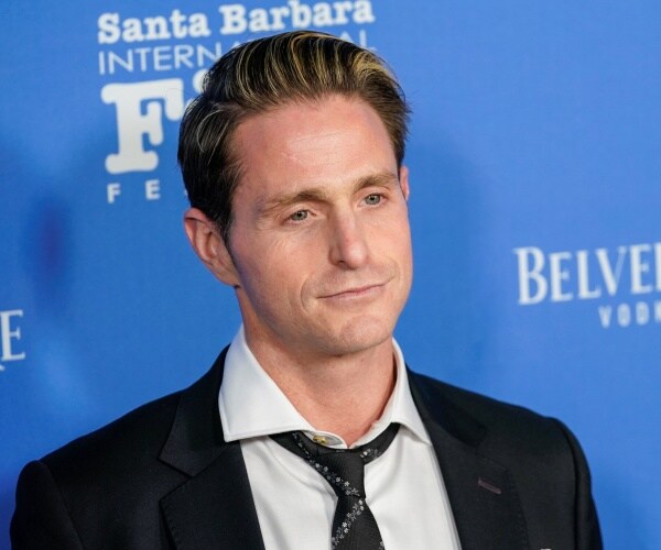 douglas in a suit and black tie with blue background