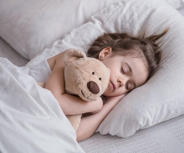 young girl asleep in bed with stuffed animal
