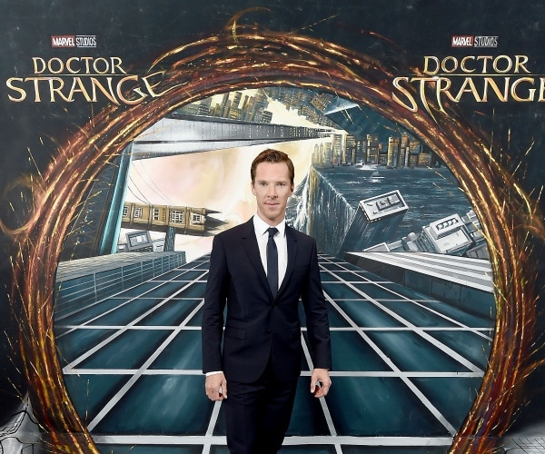 benedict cumberbatch stands in front of a dr strange sign.