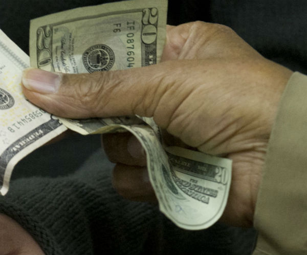 a hand holds a twenty dollar bill