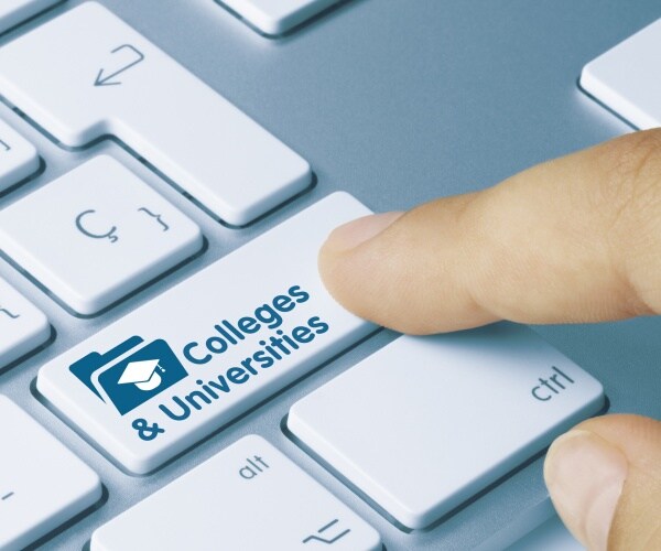 colleges and universities written on blue key of metallic keyboard with finger pressing key