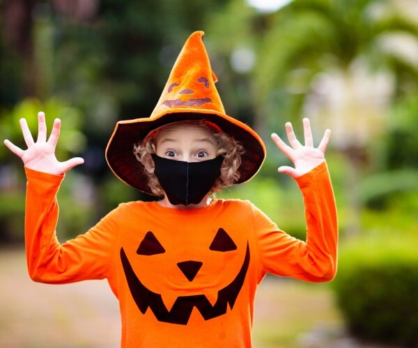 boy in pumpkin costume and black mask for COVID