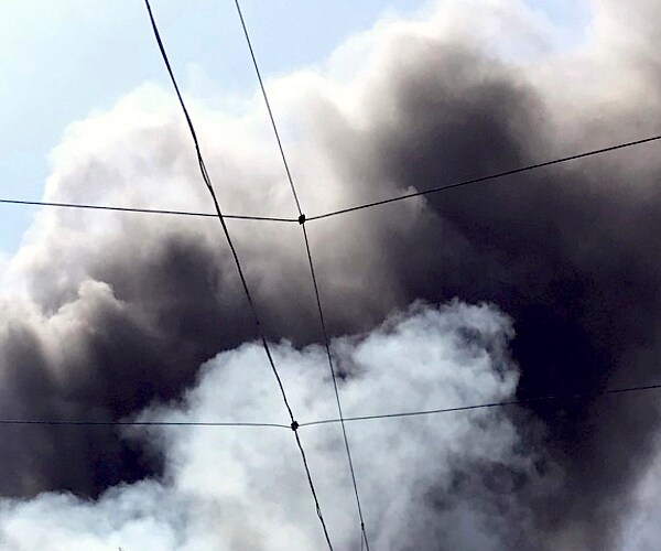 a fire casts a cloud of dense black smoke