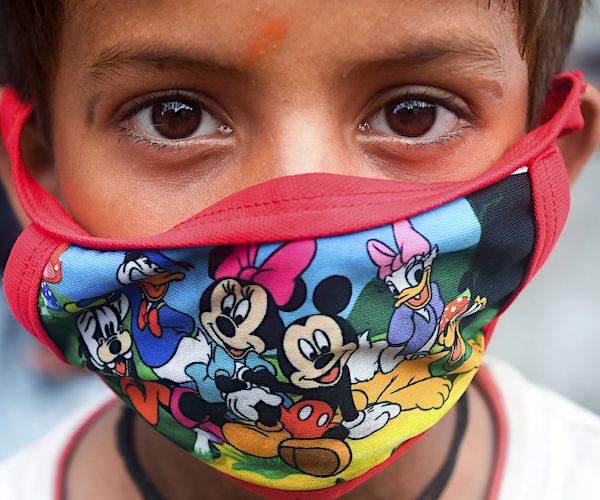 a kid wears a disney character face mask