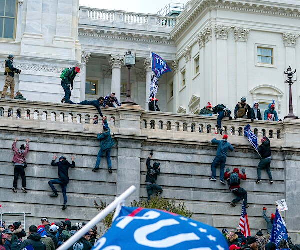 protesters storm the capitol january sixth, climbing the wall and waving trump flags