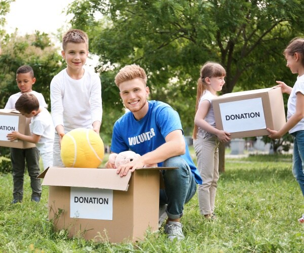 kids volunteering in park, moving donation boxes