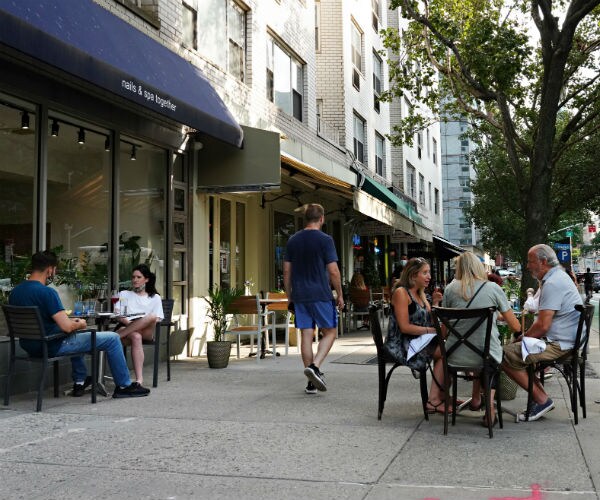 People sit at a restaurant's outdoor tables in front of a nail salon August 6, 2020 in New York City.