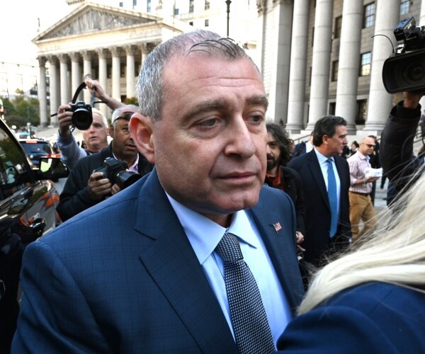 parnas in a suit and gray tie walking outside court with reporters taking photos