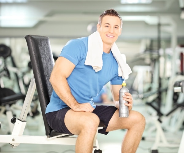 man in gym drinking water after a workout