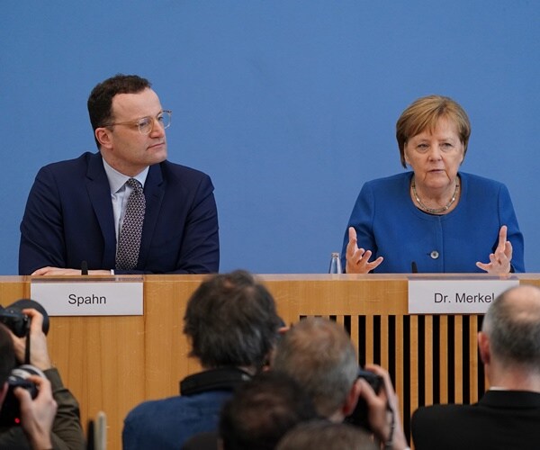 jens spah watches chancellor merkel speak